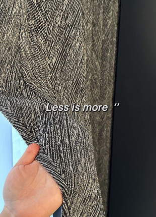 a hand holding a black and white striped fabric, with the text "Less is more" overlaid on the image.