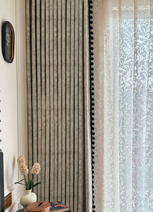 a cozy corner with a wooden table, a vase of flowers, and a book. The table is positioned next to a window with a curtain, creating a serene and inviting atmosphere.