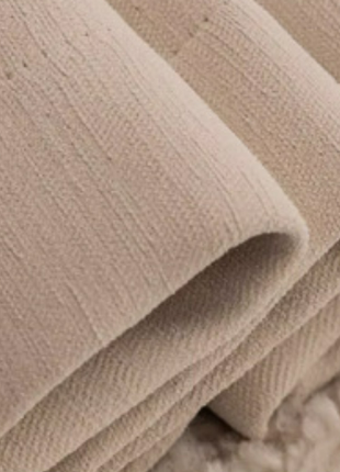 A close-up view of a folded beige fabric, possibly a blanket or towel, with a soft, fluffy texture.