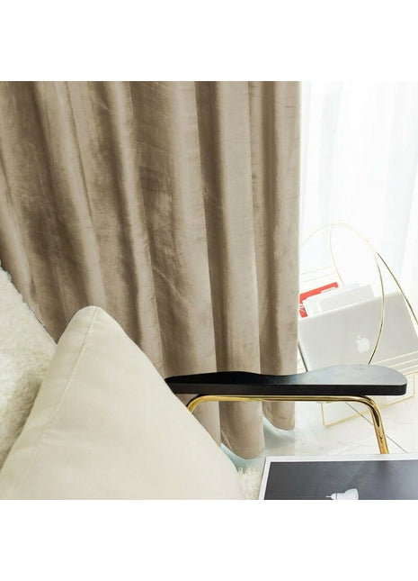 Rideau en velours taupe uni près d'un fauteuil crème et d'un guéridon doré