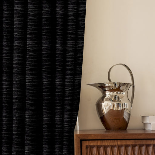 Eine silberne Vase steht auf einem Holztisch