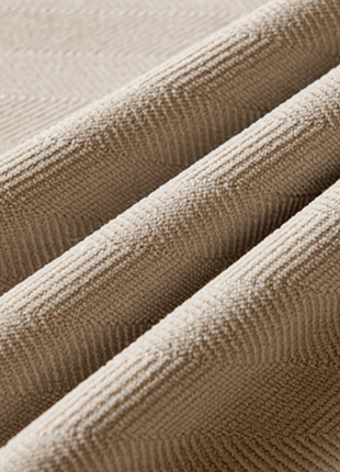 a close-up view of a fabric with a herringbone pattern, featuring three distinct folds.