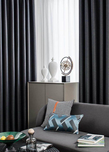 a living room with a gray couch and black curtains