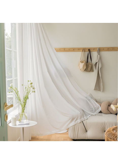 ein Wohnzimmer mit einem weißen Sofa und einem weißen Vorhang