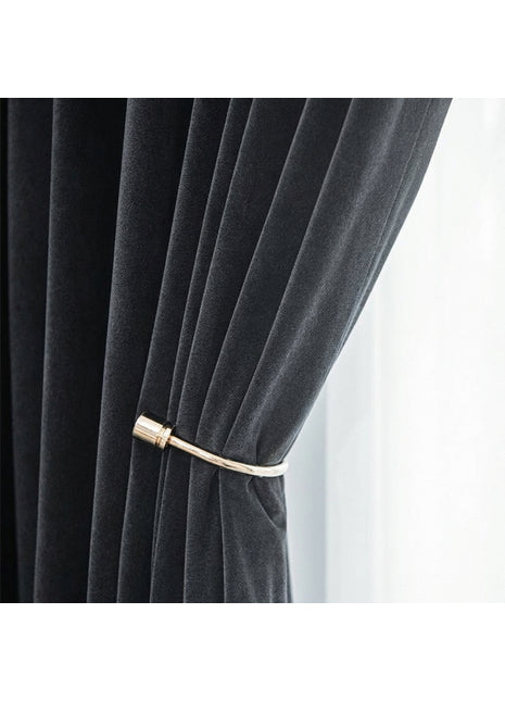 A close-up view of a black velvet curtain with a gold metal rod attached to it.