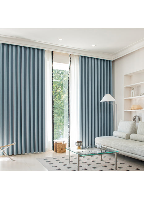 ein Wohnzimmer mit weißem Sofa und blauen Vorhängen