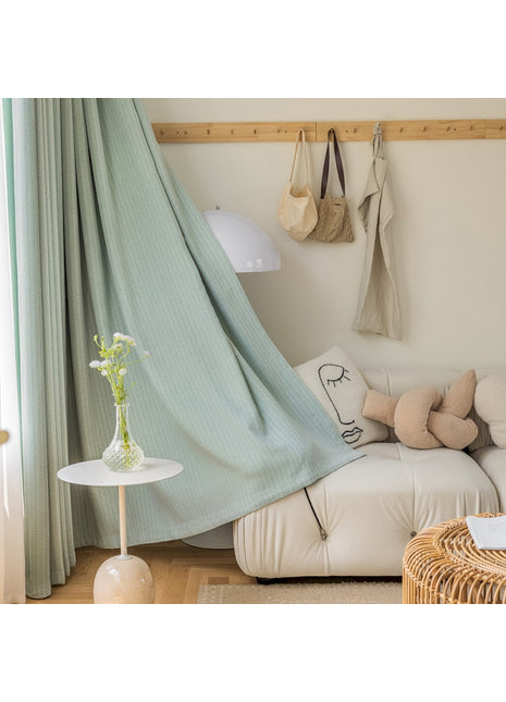 ein Wohnzimmer mit einem weißen Sofa und einem grünen Vorhang
