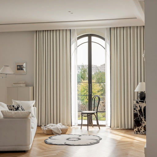 ein Wohnzimmer mit einem weißen Sofa, einem Sessel und einem Fenster