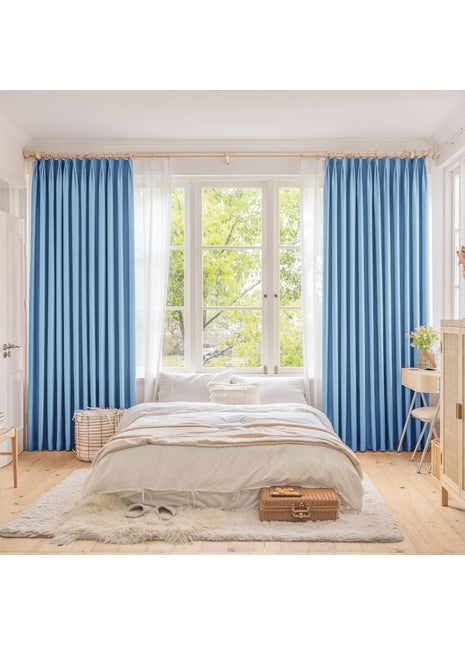 ein Schlafzimmer mit blauen Vorhängen und einem weißen Bett