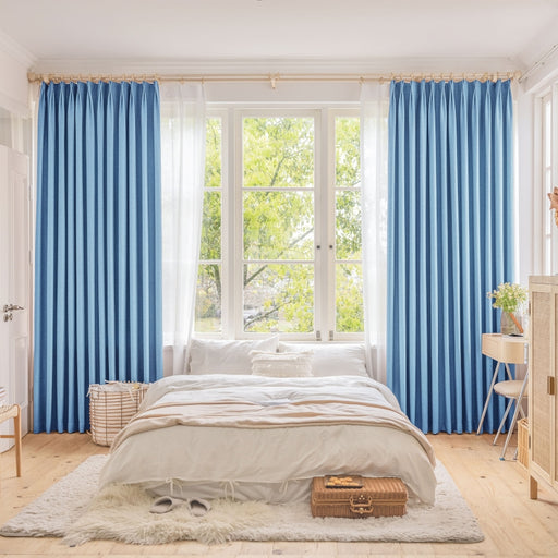 ein Schlafzimmer mit blauen Vorhängen und einem weißen Bett