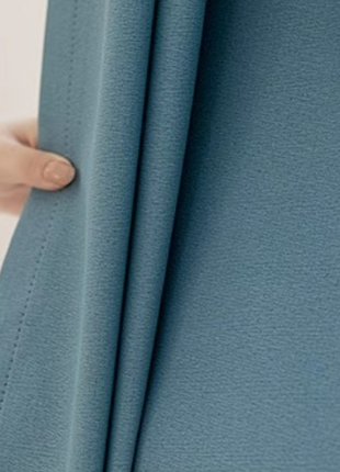 A hand is holding a blue fabric, which appears to be a piece of clothing or textile.