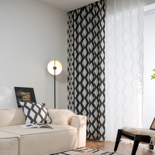 ein Wohnzimmer mit weißem Sofa und schwarz-weißen Vorhängen