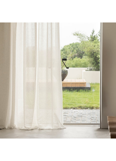 ein Fenster mit einem weißen Vorhang und einer Holzbank