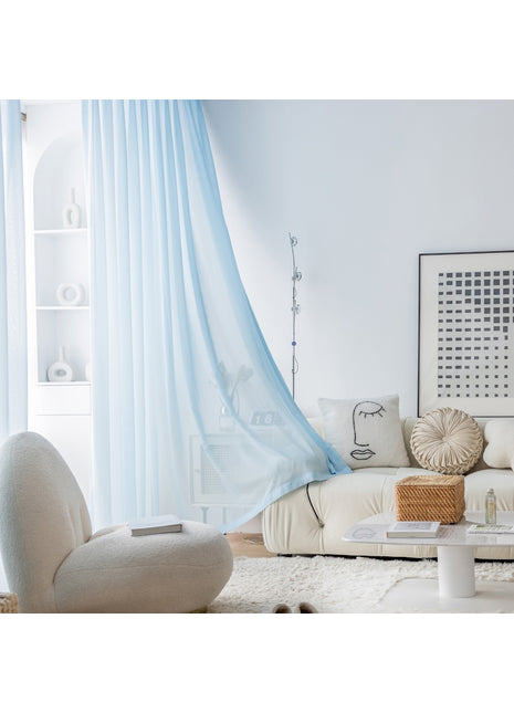 ein Wohnzimmer mit weißem Sofa und blauen Vorhängen