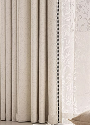 a set of cream-colored curtains with a floral pattern, hanging in a room.