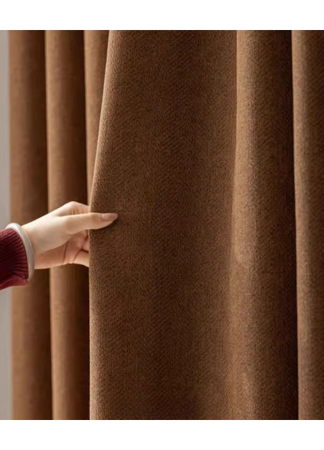 A hand is holding a brown curtain, examining its texture and color.