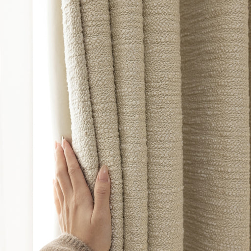 Eine Person hält einen Vorhang mit der Hand fest