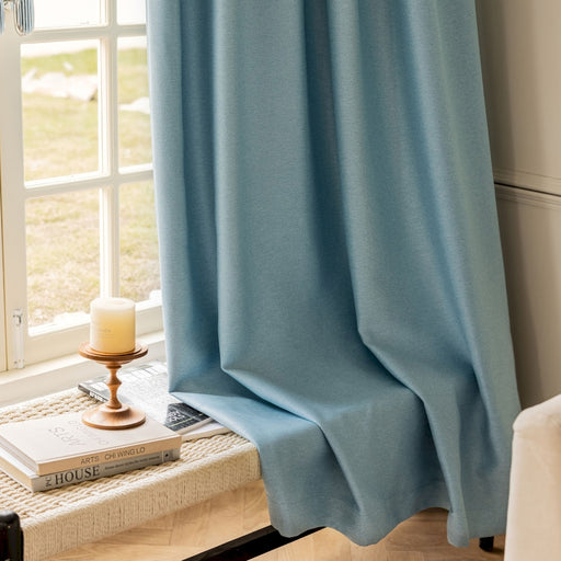 ein Fenster mit einem blauen Vorhang und einer Kerze