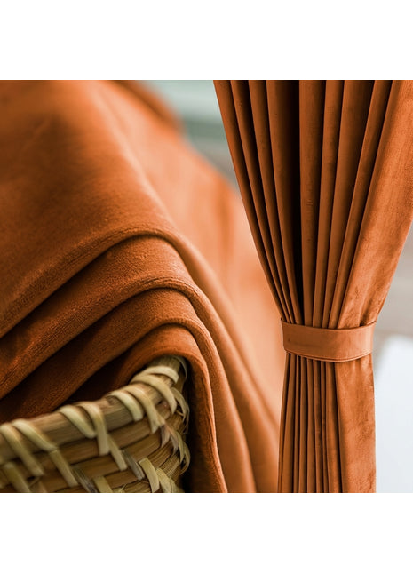 Rideau velours terracotta occultant retenu par une embrasse dans un salon, panier en rotin