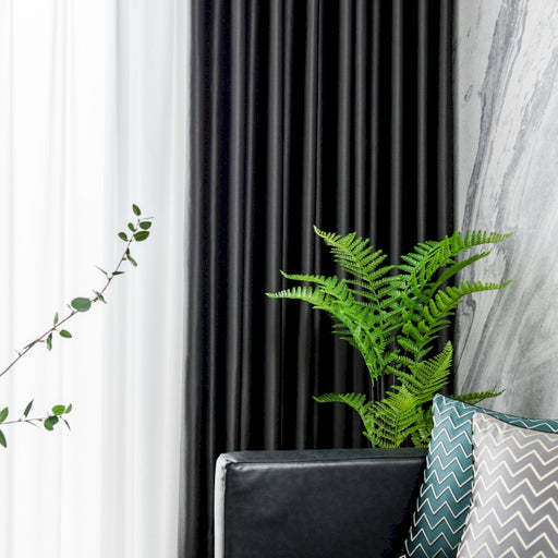 Eine grüne Pflanze steht auf einem schwarzen Stuhl