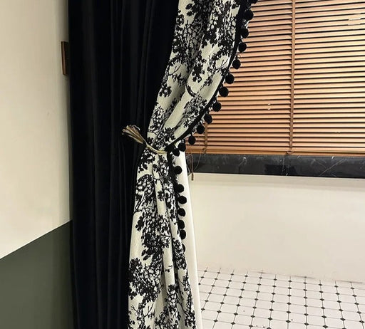 ein schwarz-weißer Vorhang mit Pomponborte