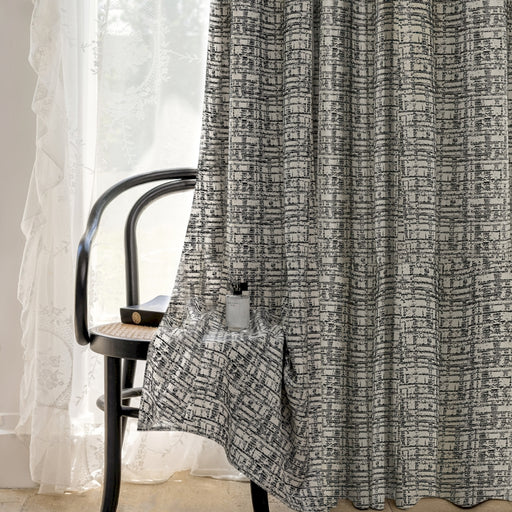 Ein Stuhl steht vor einem Fenster neben einem Vorhang.