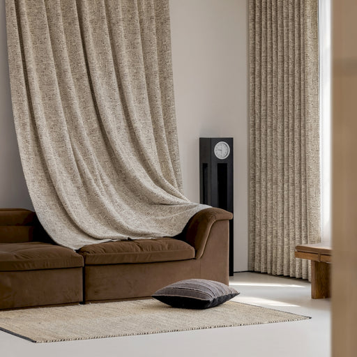 ein Wohnzimmer mit braunem Sofa und einem beigen Vorhang