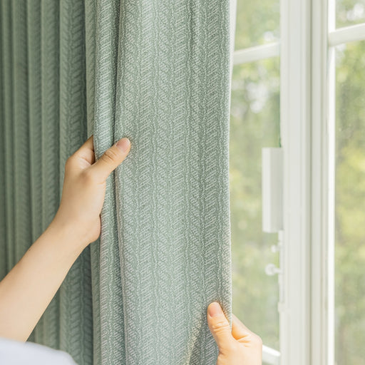a person is holding a curtain in front of a window
