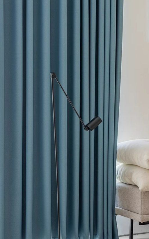 a modern living room with a blue curtain and a black floor lamp with a curved arm.
