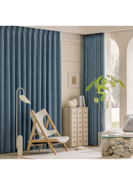 ein Wohnzimmer mit blauen Vorhängen und einem weißen Stuhl
