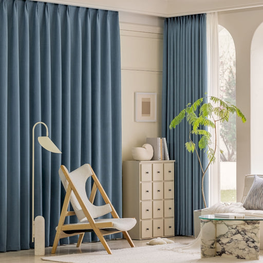 ein Wohnzimmer mit blauen Vorhängen und einem weißen Stuhl