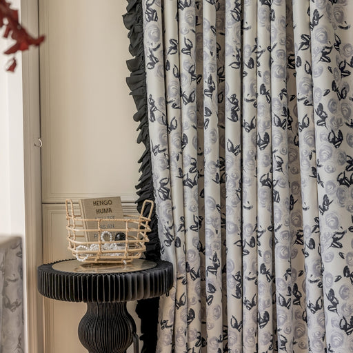 a table with a basket on top of it next to a curtain