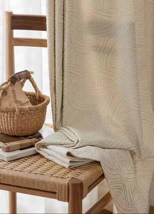 Pan du rideau blanc cassé moderne retombant sur une assise tressée en fibres naturelles