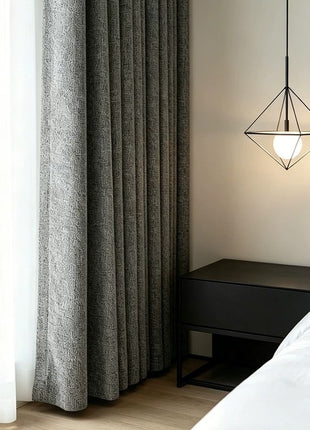 Rideau gris texturé dans une chambre contemporaine avec table de chevet noire