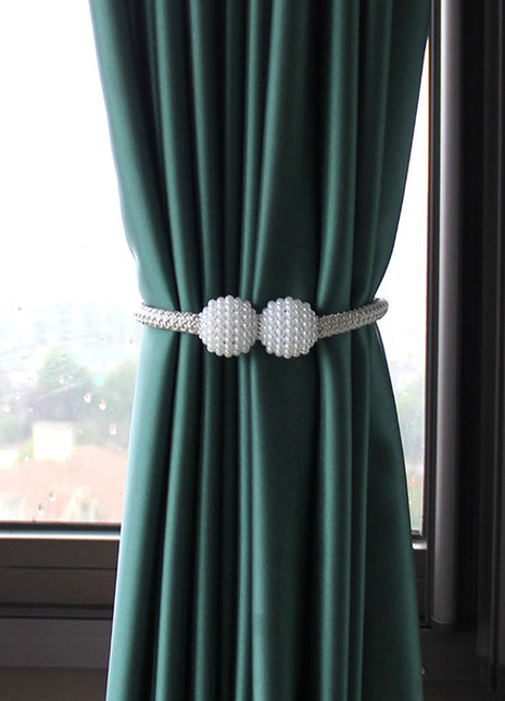 Rideau vert avec deux boules blanches, ajoutant une touche décorative à l'intérieur. Idéal sur Rideaux Déco.